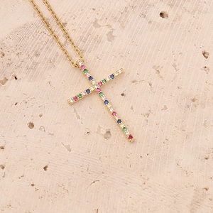 18K gold plated copper cross necklace with colorful zircon stones on textured surface