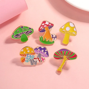 Five colorful enamel mushroom pins with gold metal edges on a soft pink background