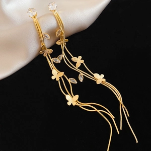 Détail de boucles d'oreilles papillon dorées à pampilles avec zircons sur fond de soie