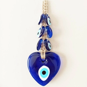 Detail of a handmade blue heart glass pendant with Evil Eye beads on beige cord