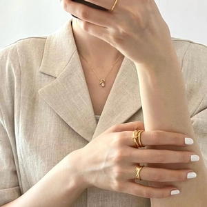 Elegant gold Saturn necklace with zircon stone and geometric rings worn by a model