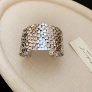 Macro shot of silver wide cuff bracelet featuring intricate woven texture and open design