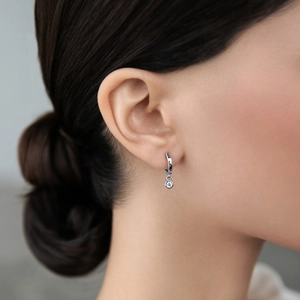 Close-up of elegant 925 sterling silver huggie hoop earring with clear zircon drop on model