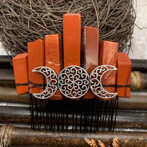 Macro shot of Red Jasper crystals and Triple Moon filigree on a handmade metal hair comb