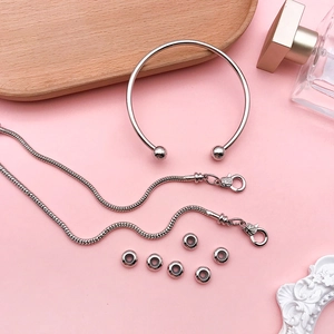 Silver bead cuff bracelet and snake chains set on pink background with elegant props