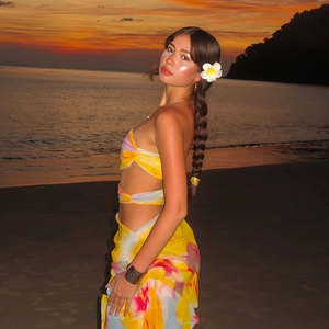 Détail du haut bandeau fleuri jaune et de la jupe paréo sur fond de coucher de soleil