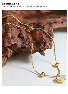 Detail of gold heart pendant bracelet with white shell inlay on a bark background