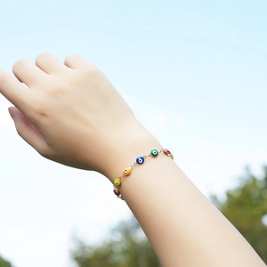 Detailed shot of gold evil eye bracelet with colorful beads worn on a wrist outdoors