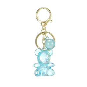 Blue transparent faceted bear keychain with glitter ball and golden ring on white background