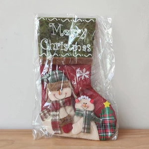 Macro detail of a red Christmas stocking featuring snowman and tree felt patterns