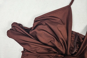Detailed close-up of dark brown fabric with subtle sheen and refined pleating details