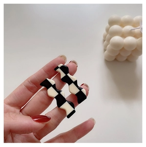 Macro shot of black and white checkered wavy earrings in polished acrylic material