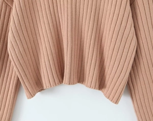 Close-up detail of apricot rib-knit texture on the sweater hem and sleeve cuffs