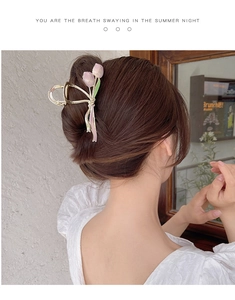 Detailed view of tulip-shaped hair claw clip in gold metal worn on a woman's hair