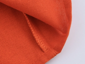 Macro shot of orange linen fabric texture with detailed stitching for summer dress