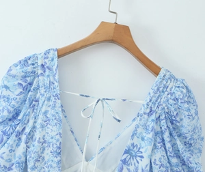 Detail of blue and white floral dress with neck tie design on wooden hanger