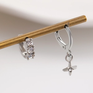 Detailed macro view of silver hoop earrings with sparkling cross charms and cubic zirconia
