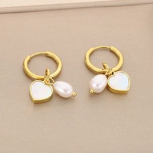 Detail of gold titanium earrings with white heart shell and round pearl charms