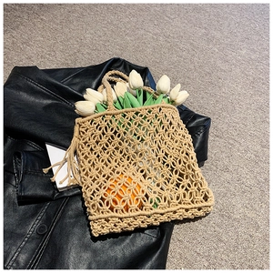 Handwoven beige crochet tote bag with hollow mesh design and fresh tulips on black jacket