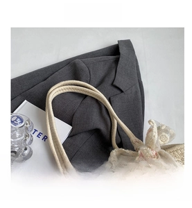 Detail view of woven straw tote bag featuring decorative lace bow and sturdy rope straps