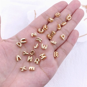 Miniature gold metal letter beads for DIY jewelry held in hand to show the small size