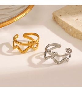 Detailed macro view of gold and silver heart rings with wavy bands on stone surface