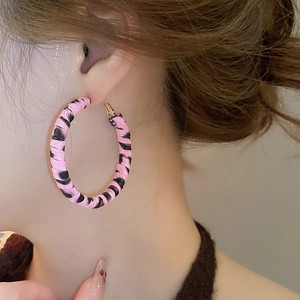Gros plan de boucles d'oreilles créoles en cuir à rayures rose et noir portées