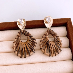 Détail des boucles d'oreilles pendantes tressées avec dorure et zircon sur coffret bijoux