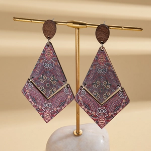 Close-up of bohemian geometric wood earrings with ethnic prints on a golden display stand
