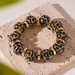 Close-up of leopard print acrylic beads and polished gold metallic spacers on stone