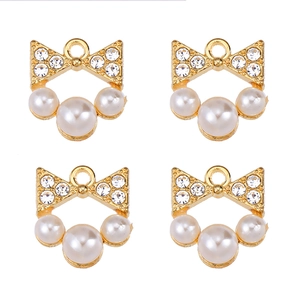 Detailed view of four golden bow charms with white pearls and sparkling rhinestones