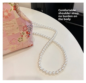 Detail of white pearl strap on pink embroidered floral pattern qipao evening bag