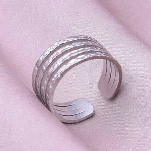 Detailed view of silver multi-layered textured stainless steel ring on pink silk fabric