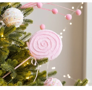 Close-up of pink and white beaded lollipop ornaments hanging on a glowing Christmas tree