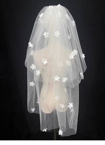 Detail of short bridal veil with delicate 3D white flowers and soft tulle texture