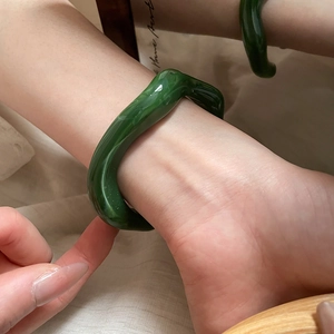 Detail showing irregular wavy green resin bangle with deep cloud-like texture on wrist