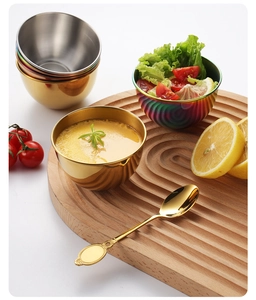 Close-up of stainless steel dipping bowls in gold and rainbow finish with matching spoons