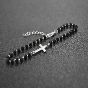 Detail of cross bracelet with black beads, silver pendant, extension chain and lobster clasp