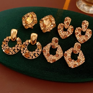 Lot de quatre boucles d'oreilles vintage dorées avec cristaux ambre sur velours vert