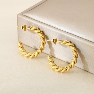 Gros plan de boucles d'oreilles torsadées en C dorées avec texture spirale unique