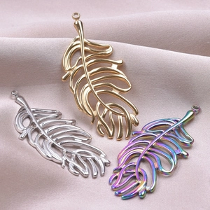 Three leaf-shaped metal pendants in gold, silver, and rainbow finishes on beige silk