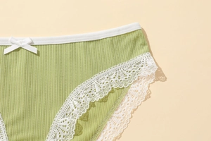 Close-up of green ribbed cotton panties featuring white lace trim and a bow detail
