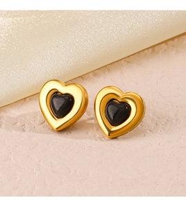 Macro detail of gold heart earrings with black cat-eye stone inlay on textured silk