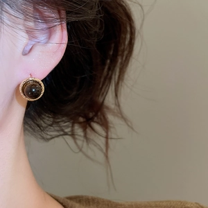 Detail of 18k gold plated earring featuring a dark gemstone and vintage metal border