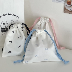 Detailed close-up of bow print drawstring storage bags in linen fabric with colorful cords