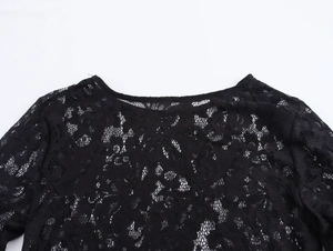 Detailed close-up of the elegant lace neckline and intricate floral patterns on a black dress