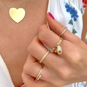 Detail of gold plated zipper ring with pavé stones and layered jewelry on model