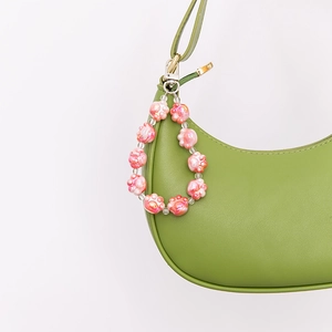 Pink cat paw beaded keychain charm on a green handbag with high gloss finish detail