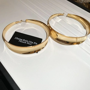 Detailed view of large gold hoop earrings with mirror finish on textured display tray