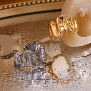 Macro shot of 18K gold and silver wavy spring rings on water surface with seashells